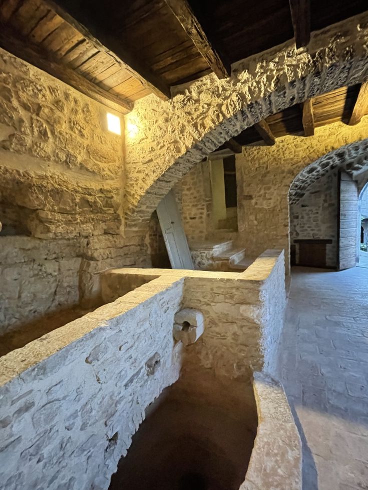 Innenräume eines Palastes im Borgo San Valentino mit Steinmauern und sichtbaren Balken, die eine gemütliche Atmosphäre schaffen.