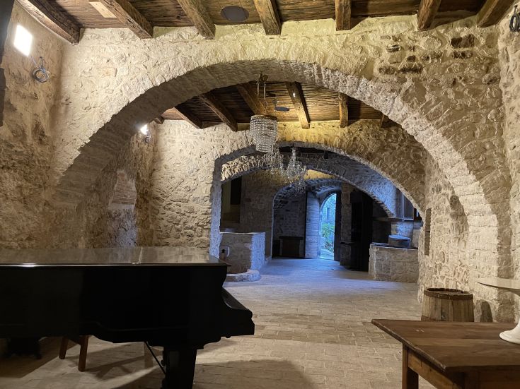 Innenräume eines Palastes in einem alten Dorf, mit sichtbaren Balken und einem Klavier in der Ecke.