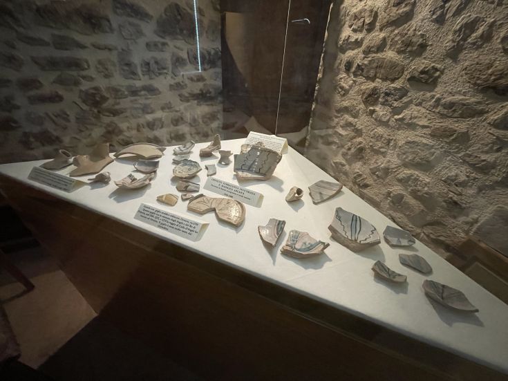 Eine Auswahl an Keramikobjekten, die in einer Vitrine präsentiert werden und aus archäologischen Ausgrabungen stammen.