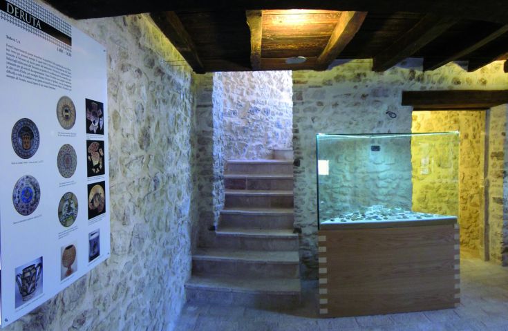 Eine Museumsausstellung mit Steinwänden und Ausstellungsräumen, ausgestattet mit einer Treppe zum Obergeschoss.