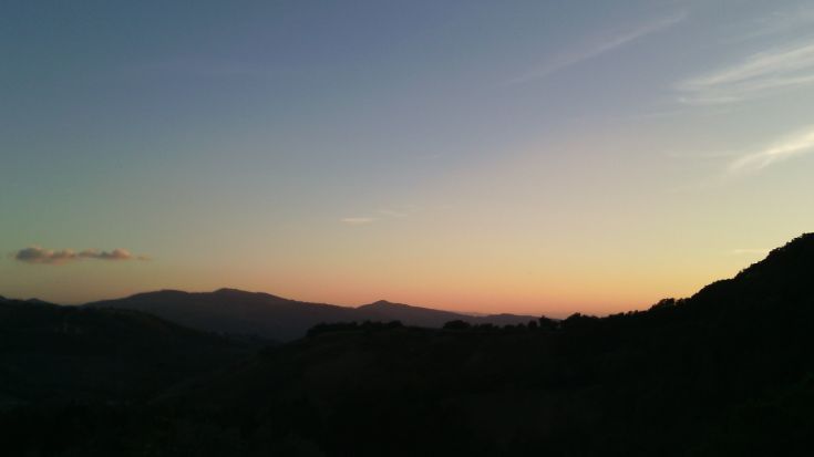 Evening scene of hills with a sky painted in shades of blue and orange.