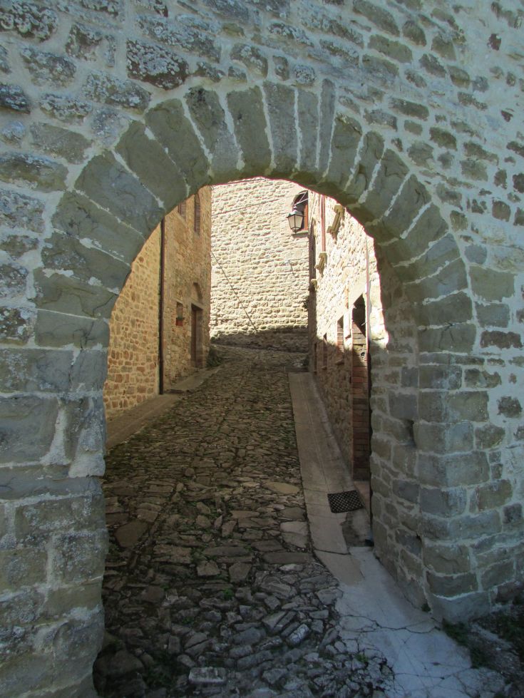 A stone alley marked by a stone arch, typical of a medieval village.