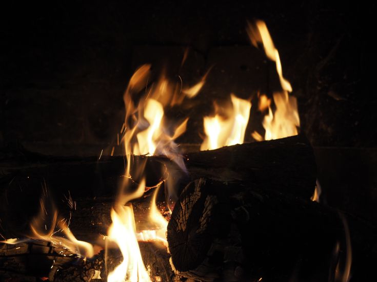 Flames burning in the fireplace, creating a warm and relaxing atmosphere for the surrounding environment.