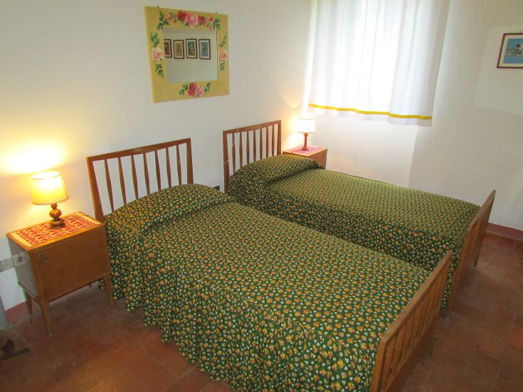 Simple room with single beds and floral decorations, well-lit and comfortable.