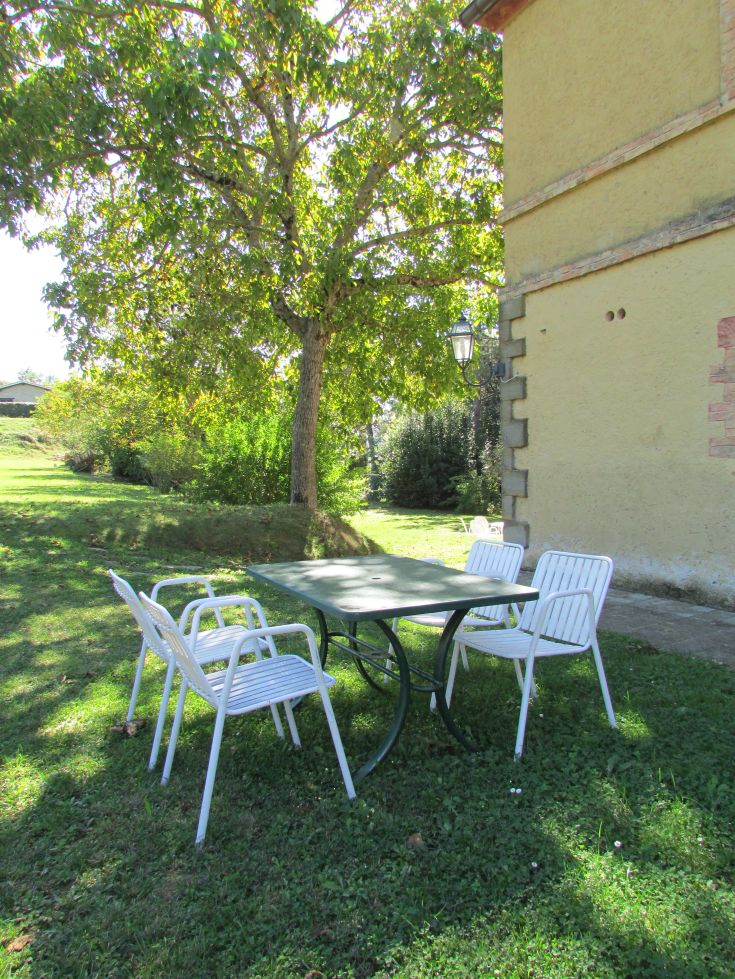A table and chairs are located in a green outdoor area, perfect for peaceful moments.