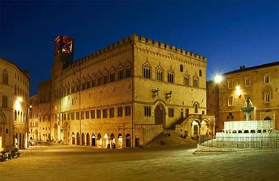 Piazza con edifici storici, illuminata di sera, che crea un'atmosfera tranquilla e ordinata.
