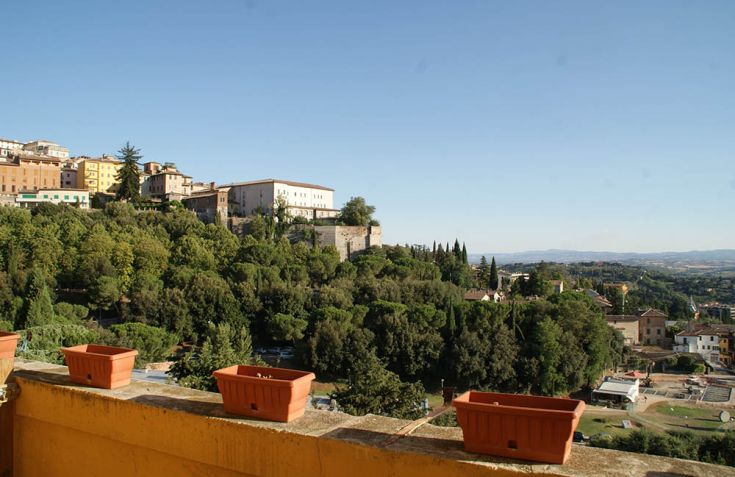 Immagine di un'area verde con edifici storici sullo sfondo, ambiente sereno e curato.