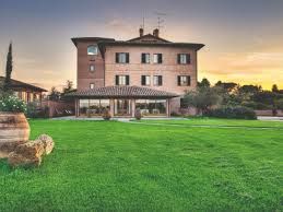 A villa set in a large green garden, with the sky fading in warm sunset colors.