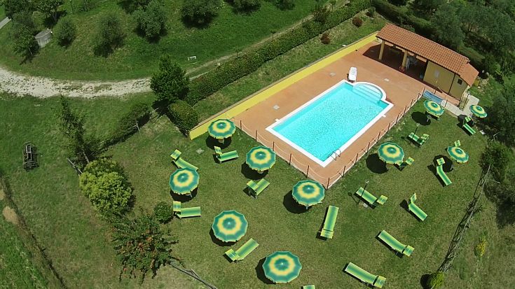 Una piscina immersa in un ampio spazio verde, attrezzata con lettini e ombrelloni per il relax.