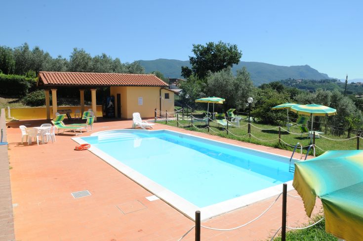Piscina immersa nella natura, circondata da dolci colline verdi, perfetta per una pausa rilassante.