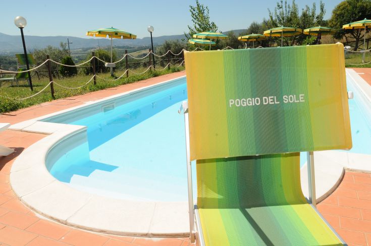 Momenti di riposo a bordo piscina in un agriturismo immerso nelle colline dell'Umbria.