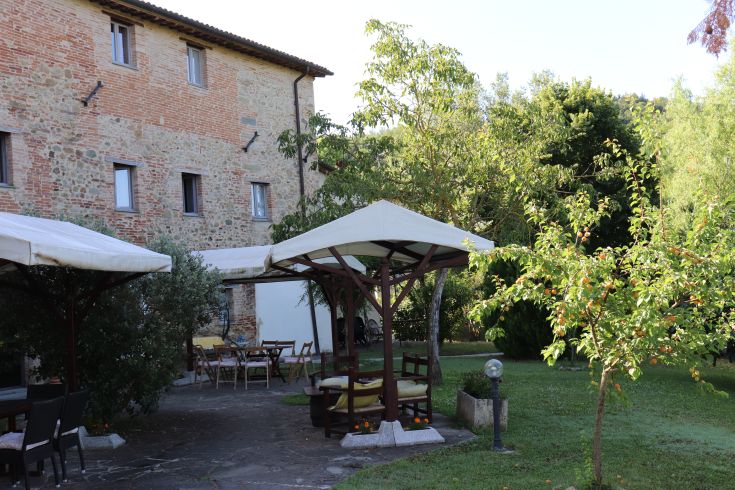 Un casale in Umbria, circondato da alberi e prati, con aree esterne dedicate al relax.
