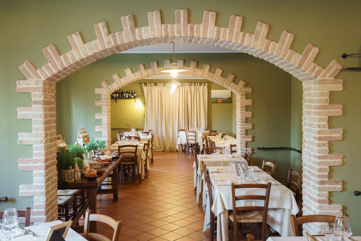 Innenraum eines rustikalen Restaurants mit gut angeordneten Tischen und einer warmen, einladenden Atmosphäre.