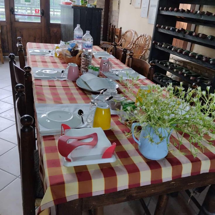 Un tavolo apparecchiato con cura all'interno di un agriturismo, pronto per offrire una semplice ma gustosa colazione.