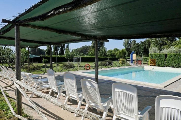 La piscina di un agriturismo, immersa in un ampio spazio verde, offre un ambiente tranquillo per il relax.