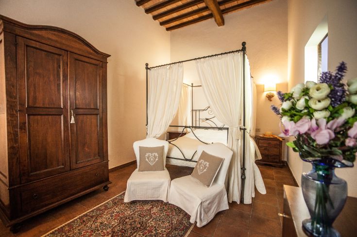Room with a canopy bed and wooden elements, situated in a serene setting.