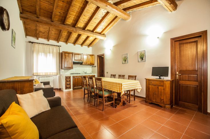 Spacious dining room with exposed wooden beams and a fully equipped kitchen, ideal for shared meals.