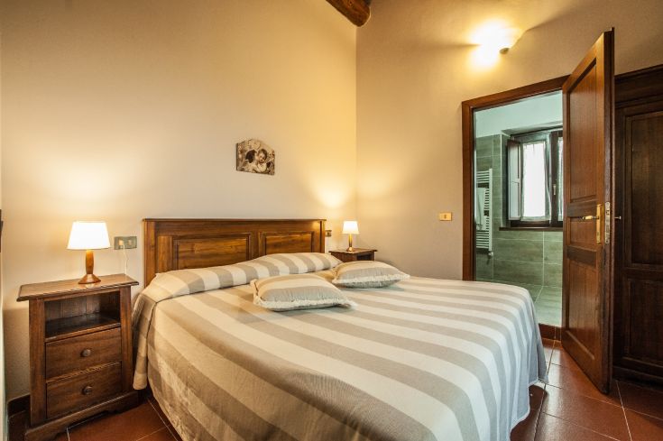Simple room with a double bed and wooden elements, perfect for a peaceful stay.
