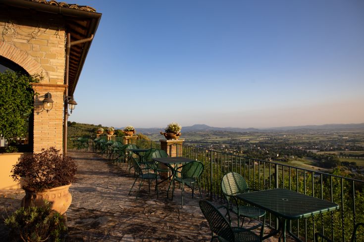 A peaceful scene featuring a furnished terrace with tables, perfect for a relaxing moment.