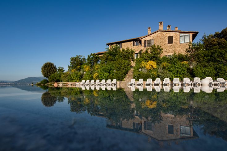 The Poggio degli Olivi is surrounded by green Umbrian countryside, featuring a pool and a restaurant serving local dishes.