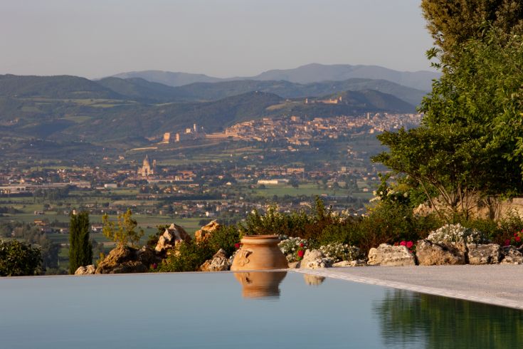 A serene scene featuring an infinity pool surrounded by gentle Umbrian hills and picturesque villages.