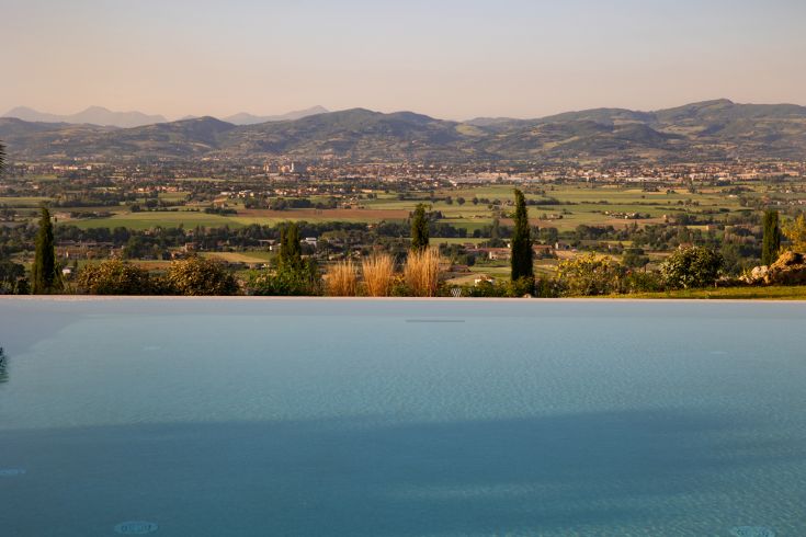 Umbrian landscape view from Poggio degli Olivi, featuring an infinity pool surrounded by nature.