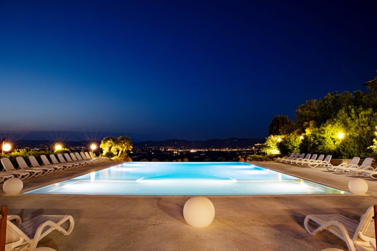Large swimming pool at sunset, with loungers available and a view of the Umbrian hills.