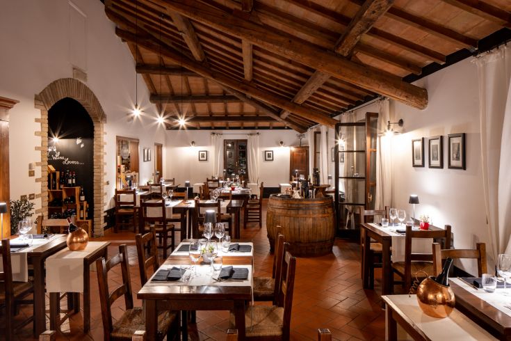 Inside of a restaurant with wooden beams, neatly arranged tables, and a warm, intimate atmosphere.