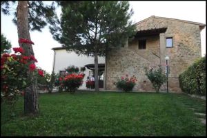 Accogliente agriturismo circondato da piante verdi e fiori colorati, situato in un ambiente naturale tranquillo.