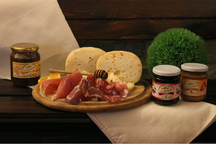 Una selezione di formaggi e salumi disposti su un tagliere, serviti con miele e confetture per un abbinamento semplice.