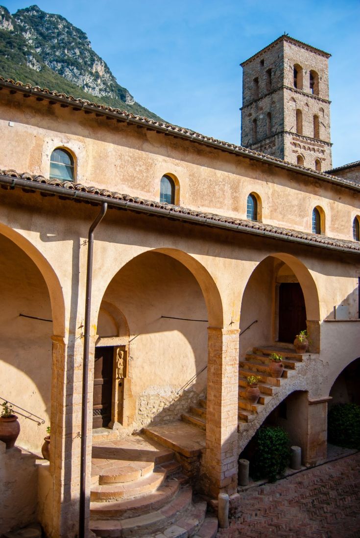 Zugang zur Abtei San Pietro in Valle, eingebettet in eine lebendige Kulisse aus Geschichte und Natur.