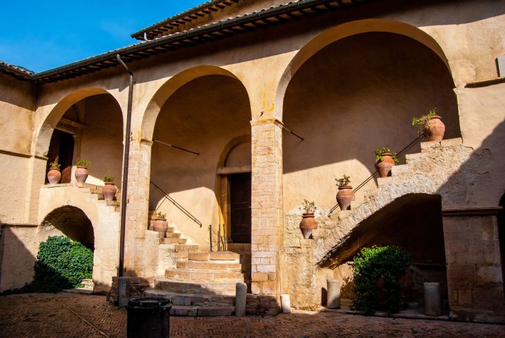 Kreuzgang mit Bögen und Topfpflanzen, ideal für einen Moment der Entspannung und Kontemplation.