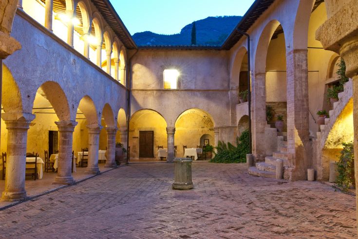 Kloster der Abtei San Pietro in Valle, umgeben von Bäumen und gepflegten Gärten.