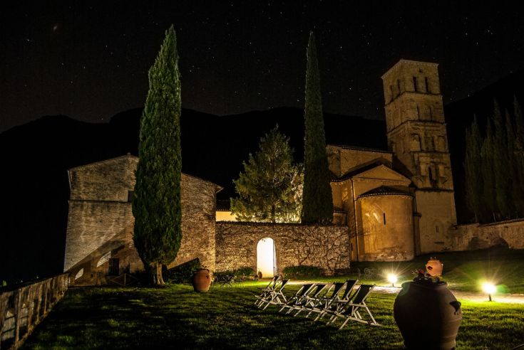 Eine historische Abtei umgeben von Bäumen, unter einem sternklaren Nachthimmel.