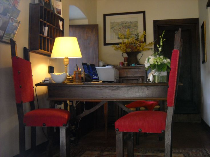 Ein einfacher Arbeitsplatz mit einem Holztisch, roten Stühlen und einer Lampe, die Licht für den Schreibtisch spendet.