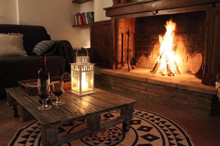 Cozy living room with a lit fireplace and a glass of wine, creating a serene atmosphere for enjoyable evenings together.