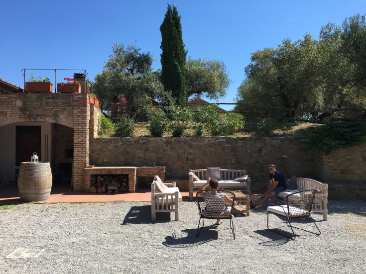 A cozy outdoor area with sofas, surrounded by lawns and trees, in a serene Umbrian countryside.