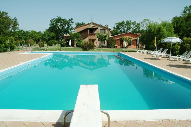A swimming pool in a garden with a renovated building in the background.