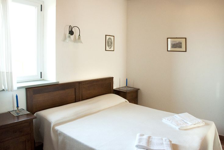 Camera spaziosa e illuminata, caratterizzata da elementi in legno e un'atmosfera calda, perfetta per un soggiorno tranquillo in Umbria.