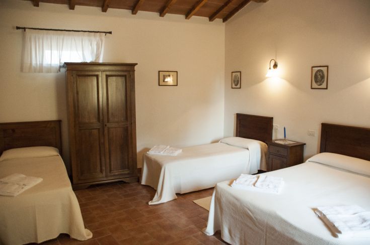 Camera semplice con letti singoli, armadio in legno e un ambiente tranquillo.