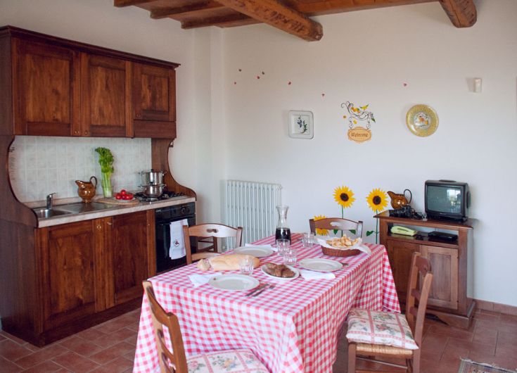 Cucina semplice e calda, con un tavolo ben apparecchiato e decorazioni in legno, perfetta per momenti in famiglia.