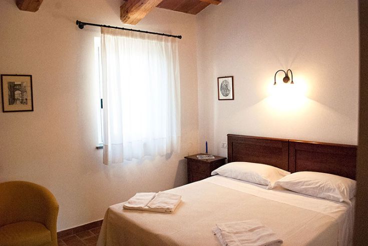 Camera semplice con letto matrimoniale e ampie finestre, adatta per un soggiorno tranquillo.