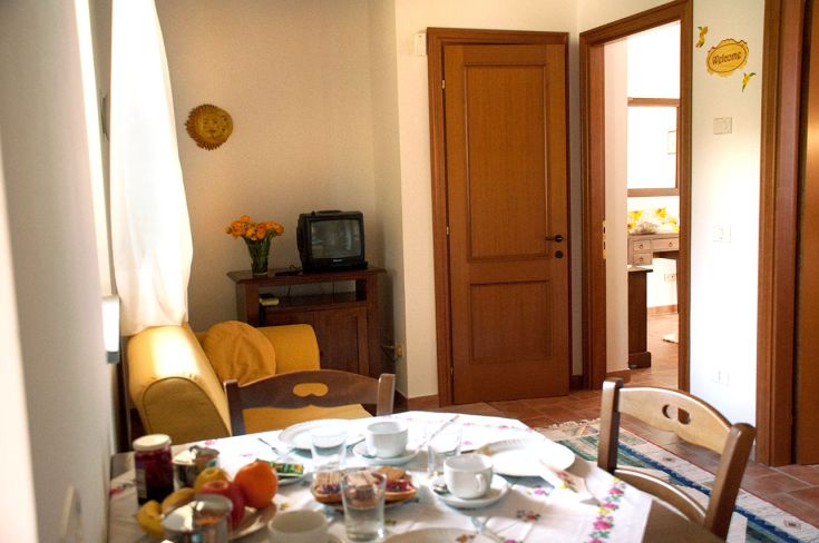 Spazio di soggiorno piacevole con tavolo allestito e panorama su un giardino curato.