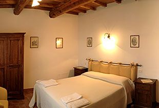 Camera ben arredata con letto matrimoniale in legno, atmosfera calda, ideale per un soggiorno confortevole.