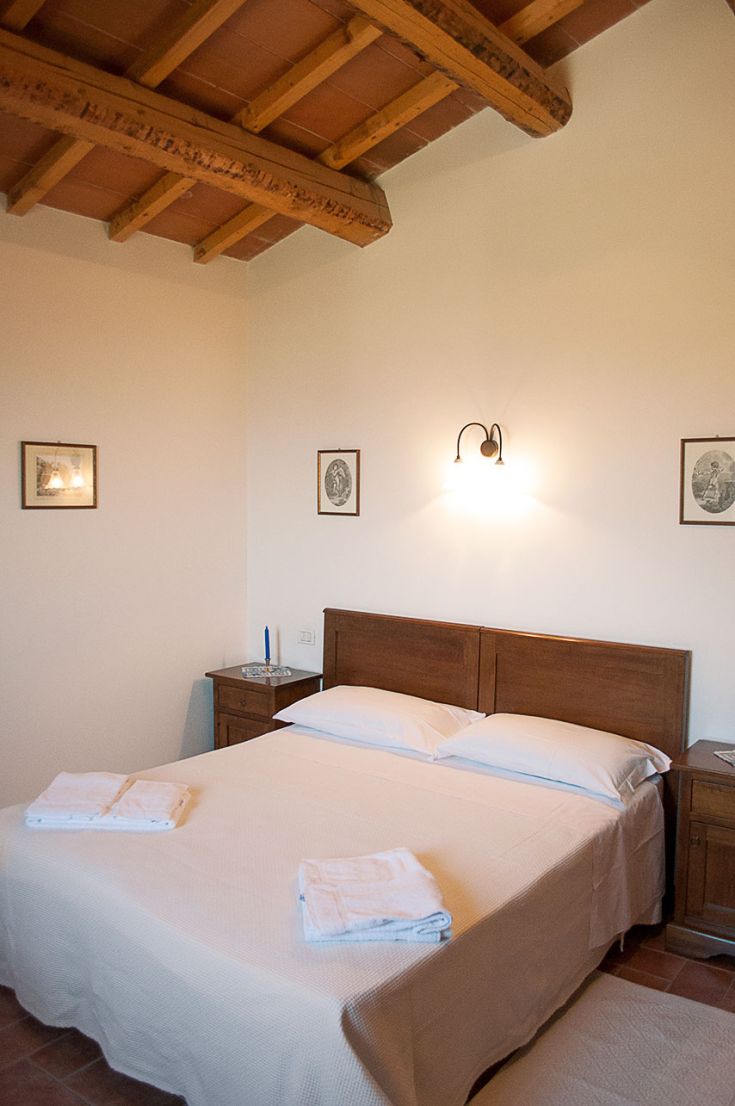 Camera semplice con arredi in stile rustico e letto matrimoniale, adatta per un soggiorno confortevole. Illuminazione calda.