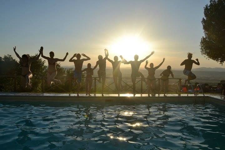 Un gruppo di persone sta saltando con gioia mentre il sole tramonta, creando un'atmosfera di festa.