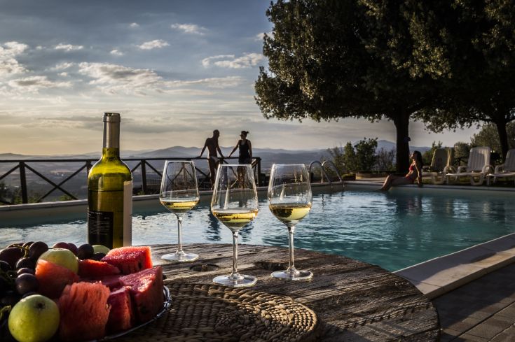 Momento di relax a bordo piscina con vino e frutta fresca, circondati dalla natura umbra.