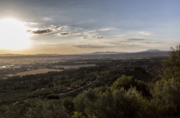 Panorama che mostra dolci colline e pianure dell'Umbria durante il tramonto, in un ambiente tranquillo.