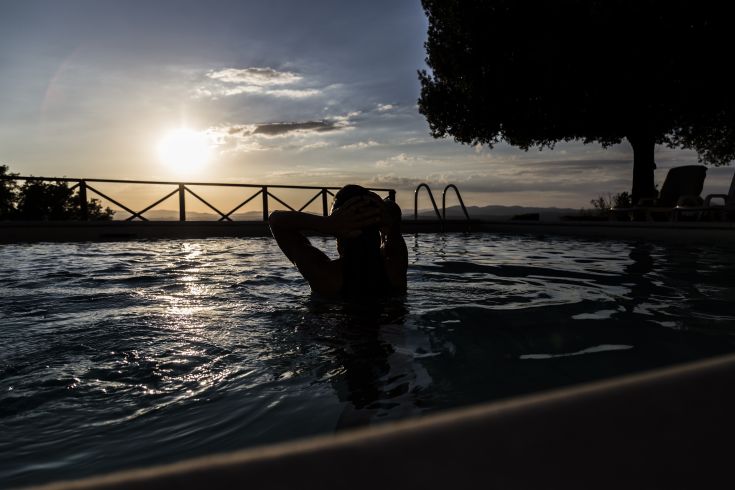 Momento di calma a bordo piscina con un panorama di tramonto sui colli umbri.