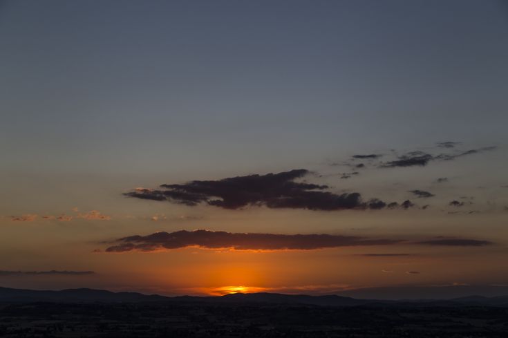 Tramonto su dolci colline umbre, presenta toni caldi e una scena tranquilla di natura.